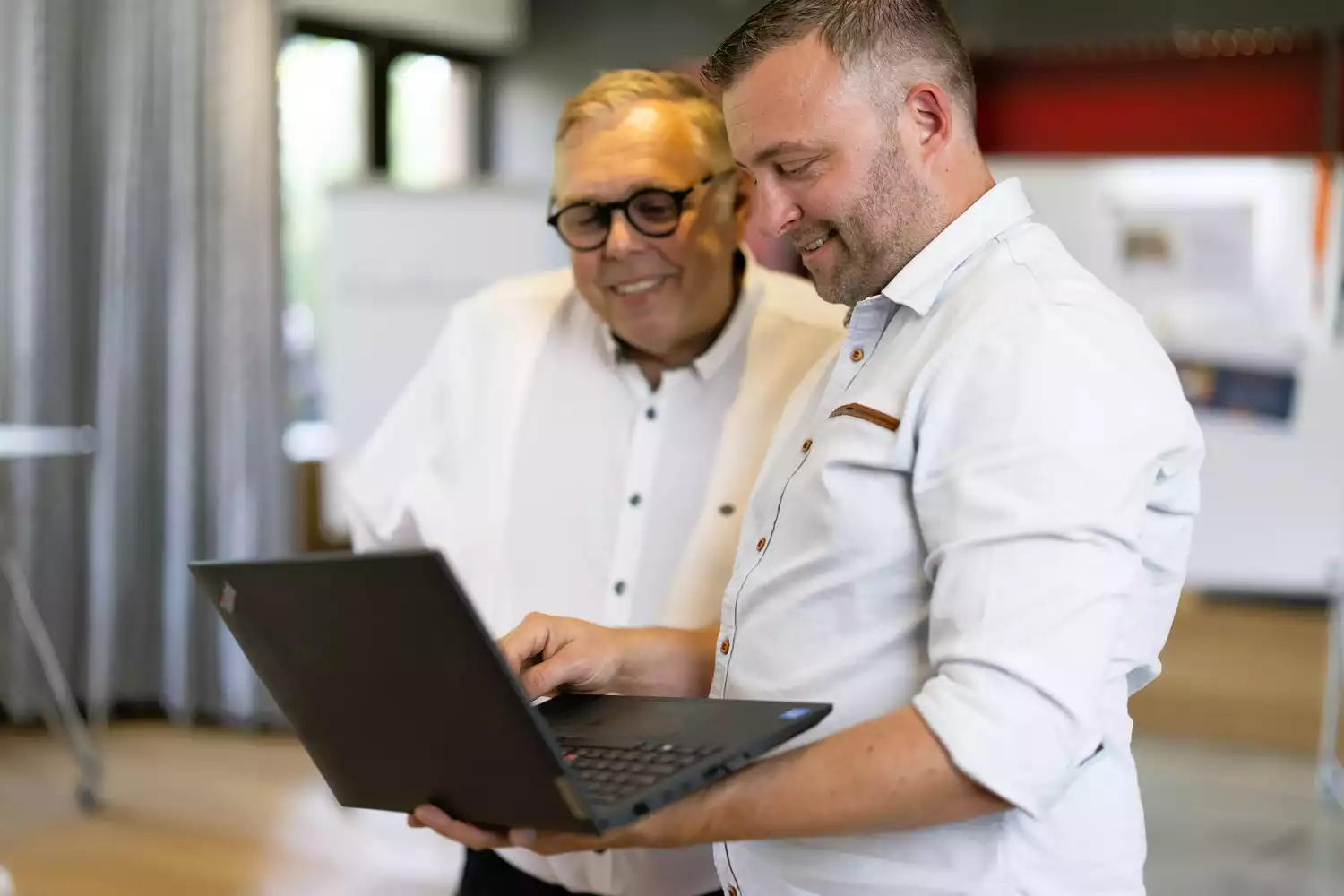 Zwei Männer im Büro schauen auf Laptop, Beratung zu IT und Digitalisierung